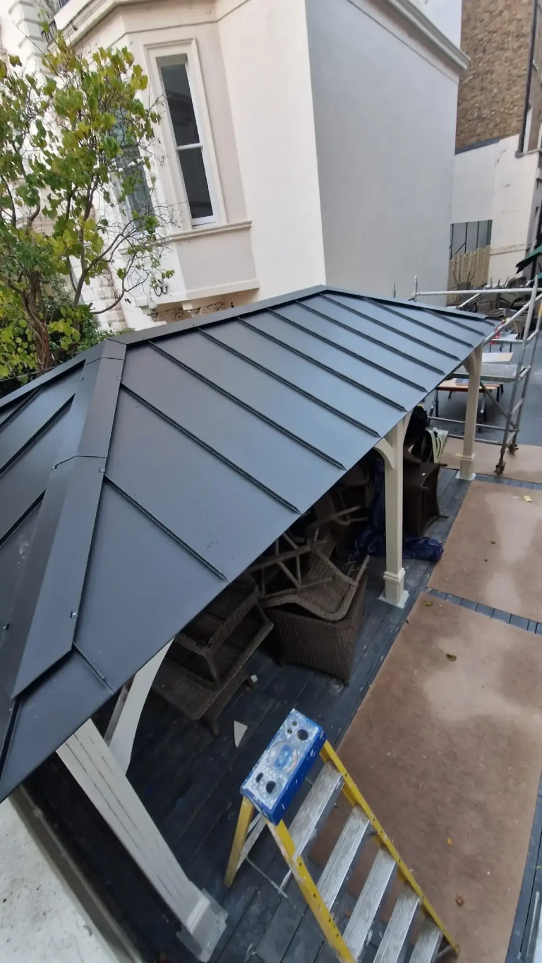 Dark standing seam zinc canopy roof over a garden structure in Putney